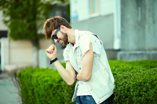 Funny smiling hipster handsome man guy in stylish cloth in the street in sunglasses