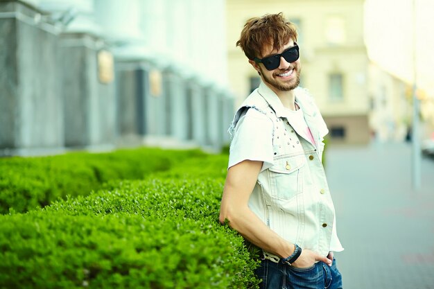 Funny smiling hipster handsome man guy in stylish summer cloth in the street in sunglasses