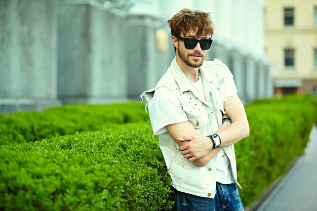 Funny smiling hipster handsome man guy in stylish summer cloth in the street in sunglasses