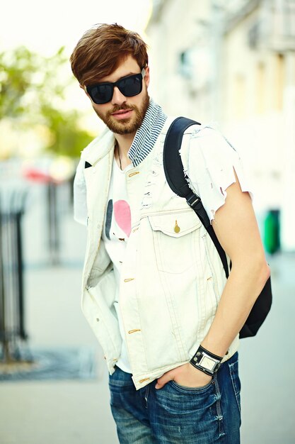 Funny smiling hipster handsome man in stylish summer cloth in the street in sunglasses