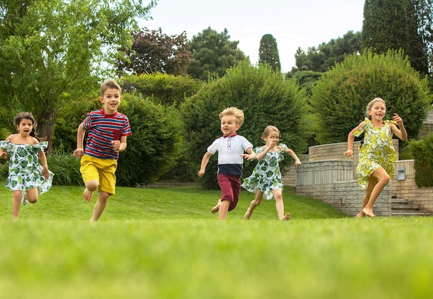 Funny starts. Kids fashion concept. group of teen boys and girls running at park. Children colorful clothes, lifestyle, trendy colors concepts.