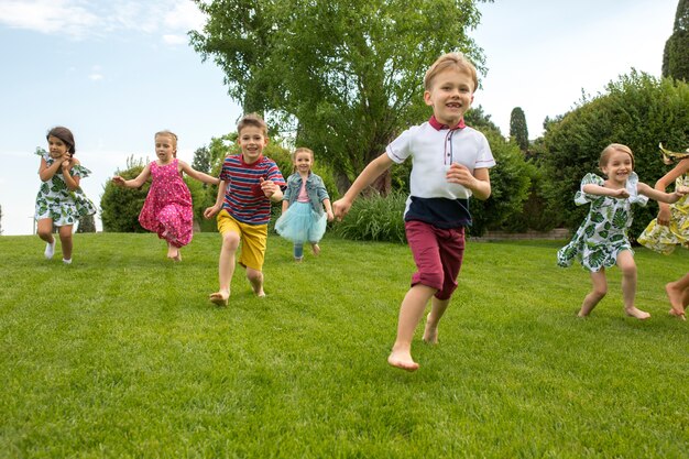 Смешные старты. Концепция детской моды. Группа мальчиков и девочек-подростков, бегущих в парке.