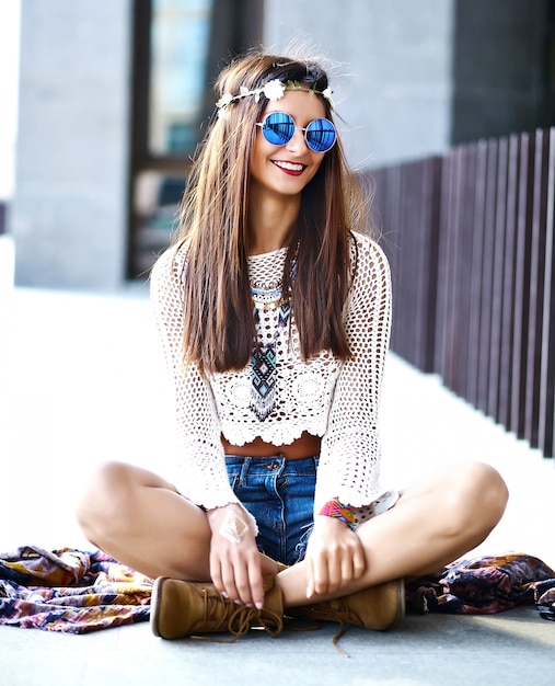 Funny stylish sexy smiling beautiful young hippie woman model in summer white hipster clothes posing in the street