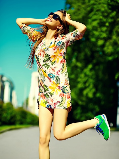 通りでジャンプ夏明るい流行に敏感な布ドレスで面白いスタイリッシュなセクシーな笑顔の美しい若い女性モデル