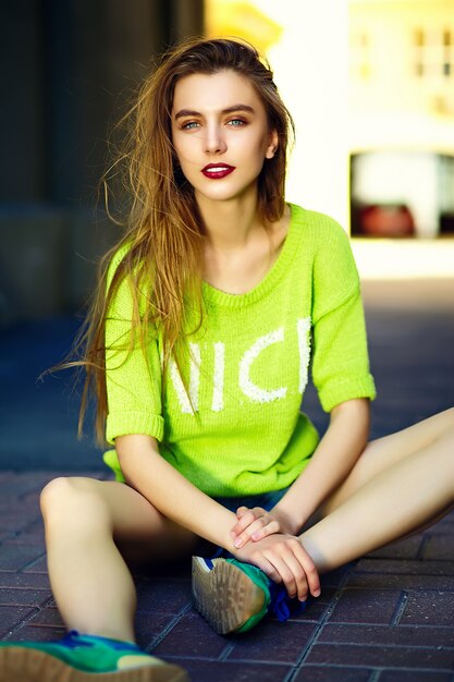 Смешная стильная сексуальная улыбающаяся красивая модель молодой женщины летом ярко-желтая хипстерская ткань, сидящая на улице