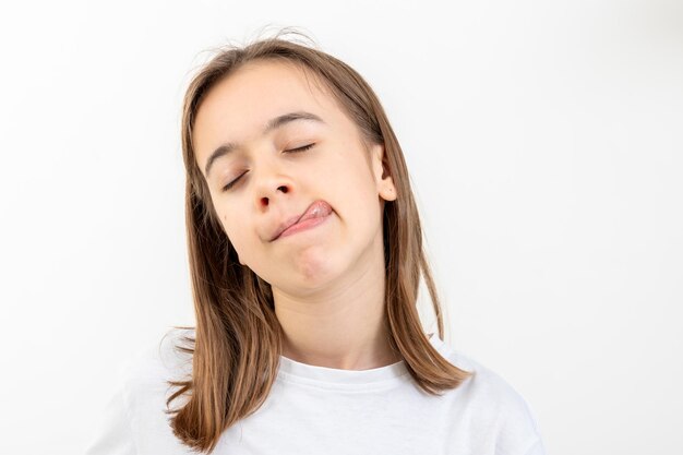 Funny teenage girl licks her lips on a white background isolated