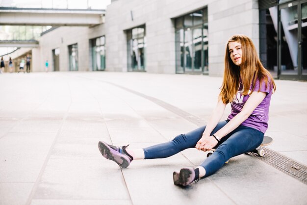 Funny teenager sitting on skateboard