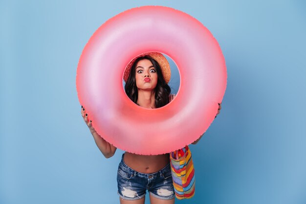 Funny woman in denim shorts holding pink swimming circle