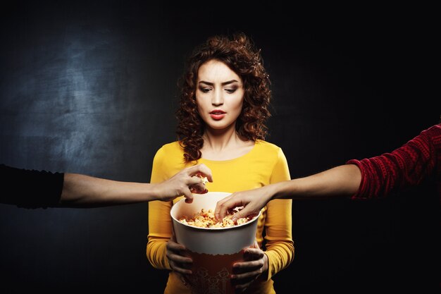 Funny woman doesn't like sharing snacks with friends at cinema