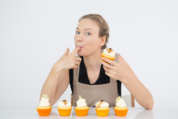 Free photo funny woman licking finger with buttercream