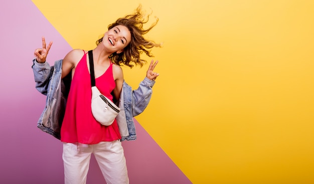 Funny woman with short wavy hairs dancing and having fun on multicolor.