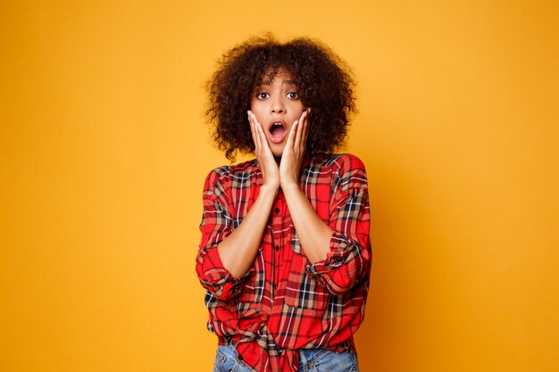 Funny  young african woman posing isolated over  orange  background. Surprise face. Studio shot.