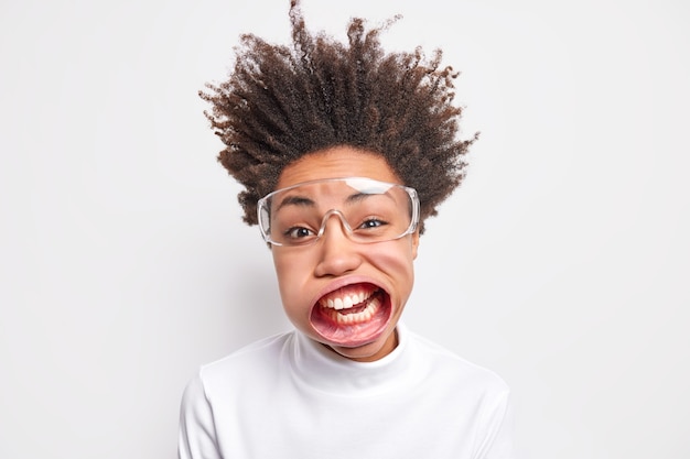 Free photo funny young afro american woman has wide opened mouth wears transparent glasses, exclaims loudly.