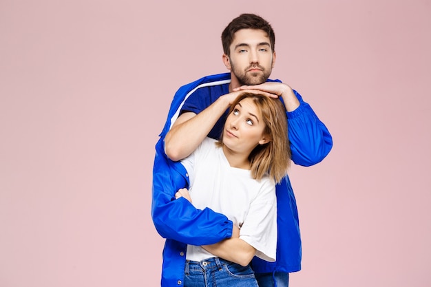 Free photo funny young beautiful couple wearing one jacket  over light pink wall