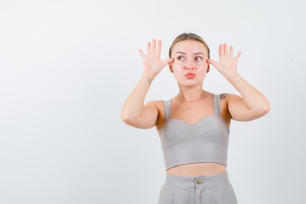 La ragazza divertente sta indicando i gesti delle mani su sfondo bianco