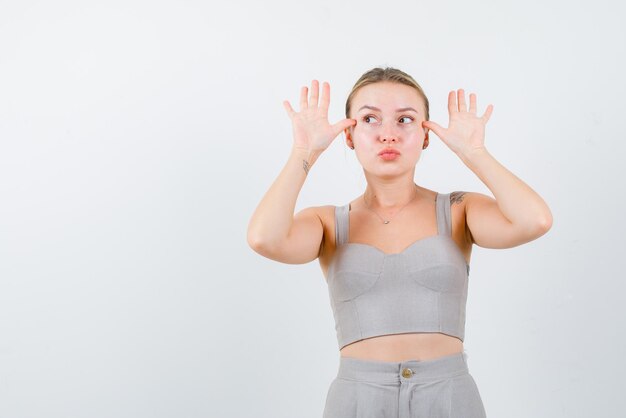 The funny young girl is poinitng hand gestures on white background