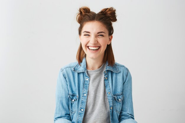 Funny young happy cheerful girl with two buns laughing smiling .