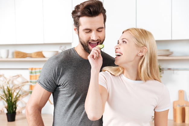 Funny young loving couple standing at kitchen and cooking