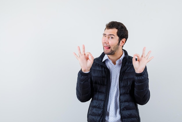 The funny young man is showing okay gesture with hands on white background