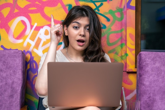 Забавная молодая женщина перед ноутбуком с удивленным взглядом