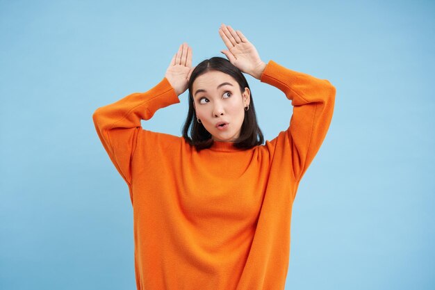 Free photo funny young woman shows ears gesture above head and dancing looking cute and silly playing standing