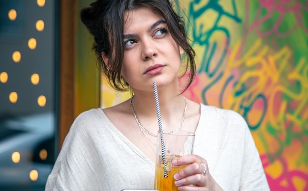 Funny young woman talking on the phone with a glass of lemonade