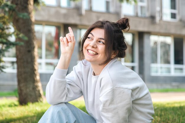 Funny young woman with a bun on her head in a city park