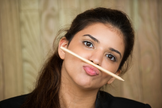 Divertente giovane donna con matita tra labbro e naso