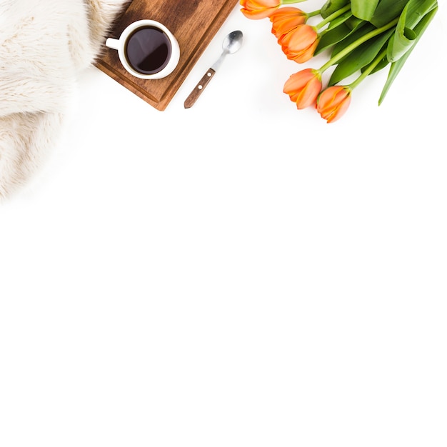 Fur; spoon; coffee cup and an orange tulip bouquet on white background