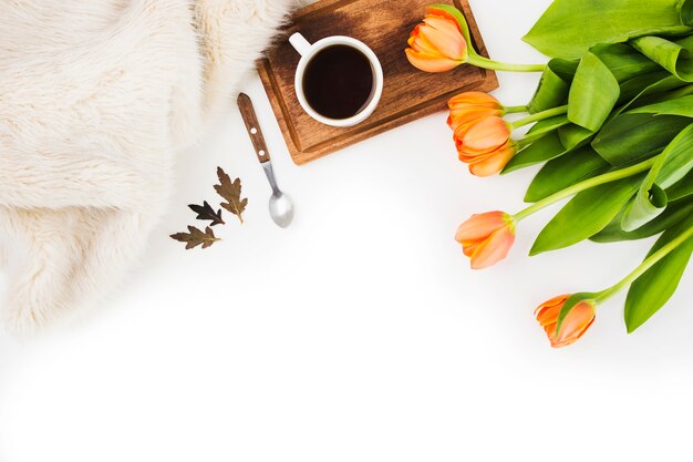 Fur; spoon; coffee cup and an orange tulips on white background