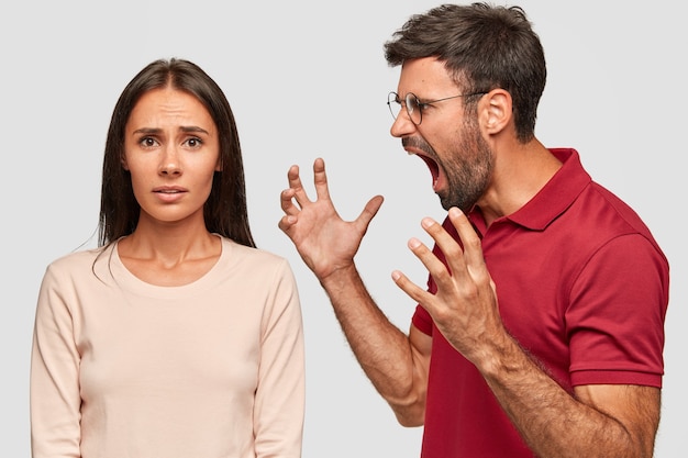 Furious bearded guy screams and gestures angrily, yells at woman, have dispute, pose together