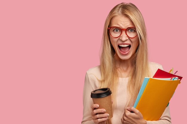 Furious blonde woman yells with madness, being discontent with exam results after long preparation