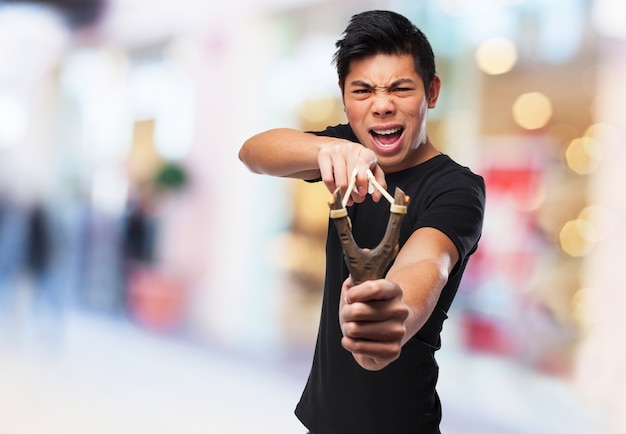 Free photo furious boy playing with his slingshot