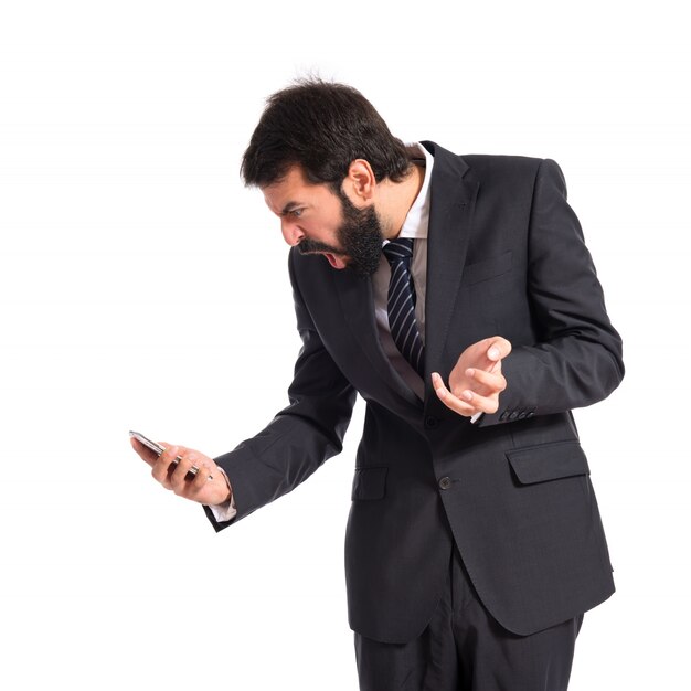 Furious businessman talking to mobile over white background