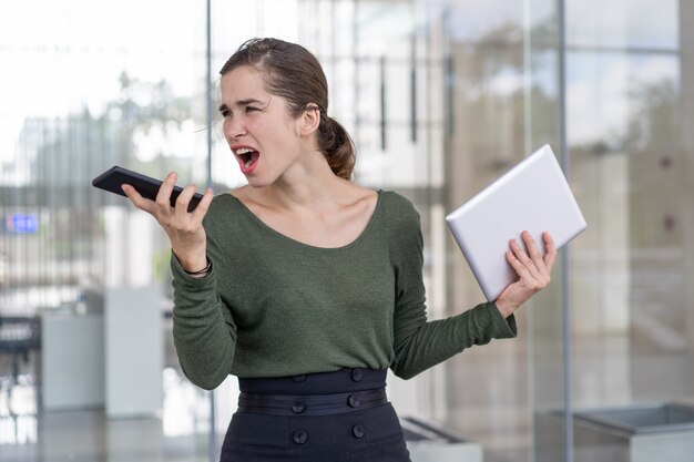 Furious businesswoman yelling at partner on speakerphone