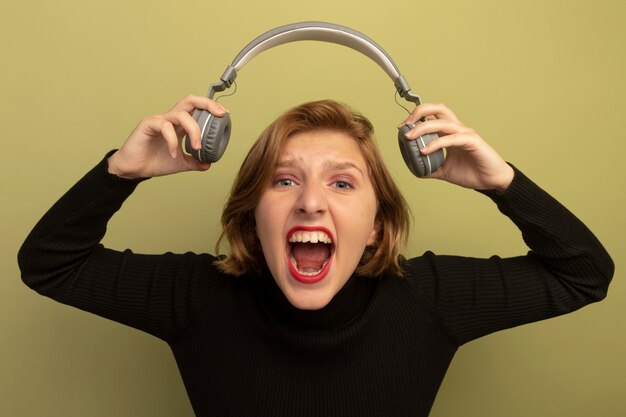 Furious young blonde girl holding headphones 