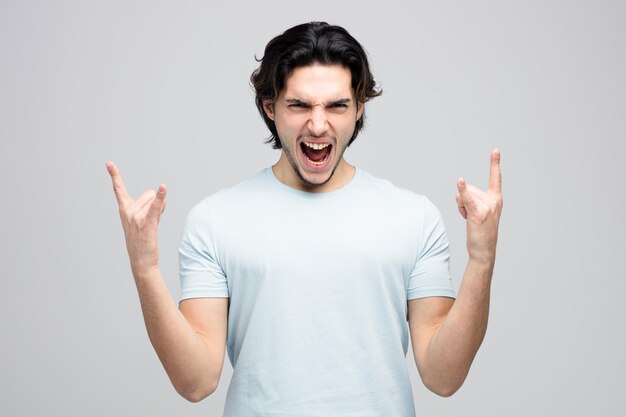 furious young handsome man looking at camera showing rock sign screaming isolated on white background