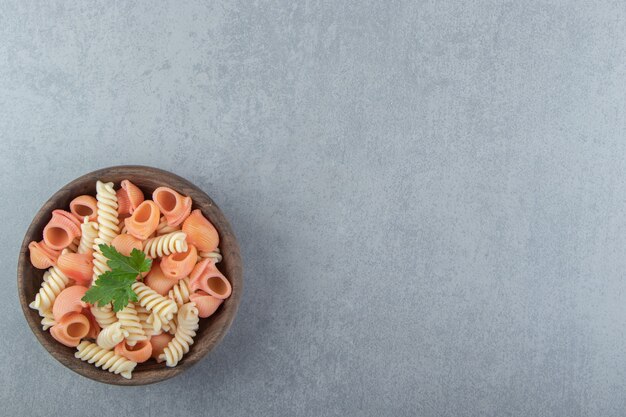 Fusilli and cochiglie pasta in wooden bowl.