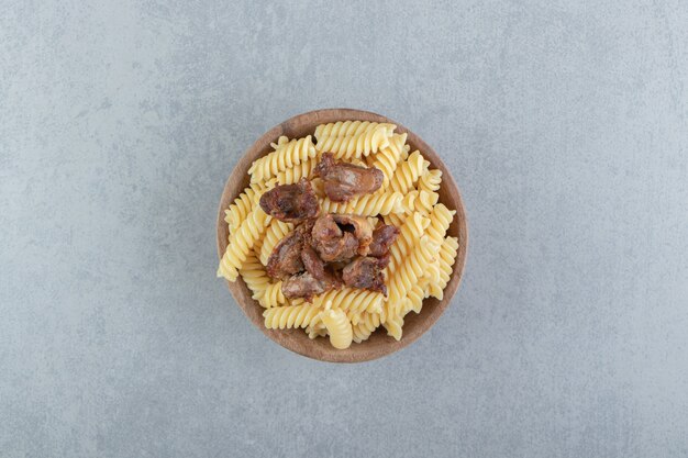 Fusilli and fried chicken in wooden bowl.