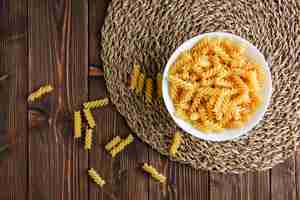 Foto gratuita fusilli in una ciotola su tovaglietta di legno e vimini, piatto laici.