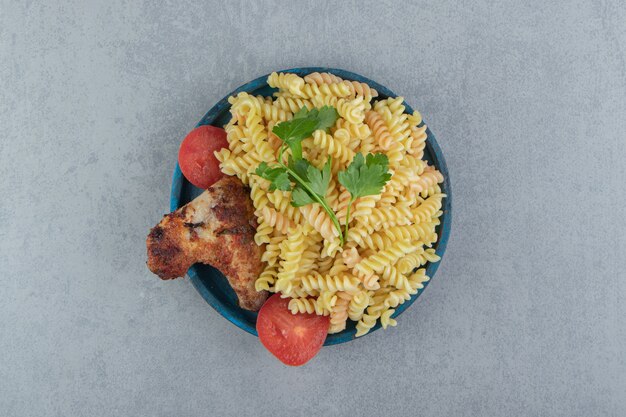 Fusilli pasta and chicken wing on blue plate.