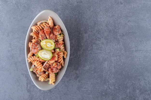 Fusilli pasta with chicken in ceramic bowl.