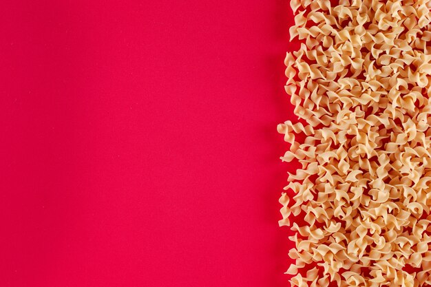 fusilli pasta with copy space on the right of pink red surface