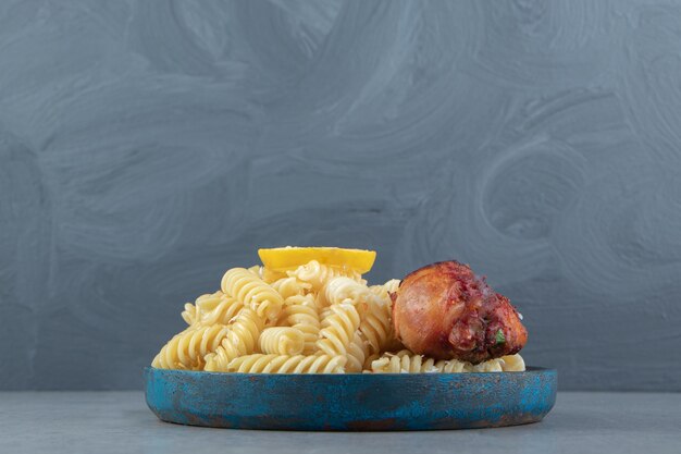 Fusilli pasta with fried chicken on blue plate.