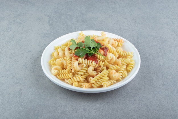 Fusilli pasta with sauce on white plate.