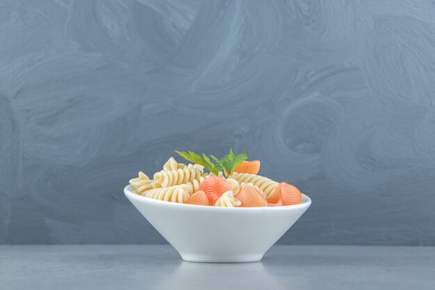 Fusilli e pasta di conchiglie in ciotola bianca.