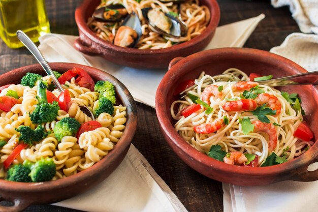 Fusilli and spaghetti pasta in earthenware on table with napkins