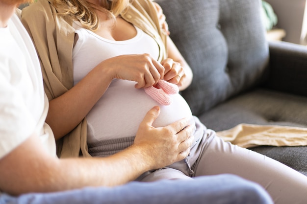 Foto gratuita madre futura che applica le scarpe della neonata alla pancia