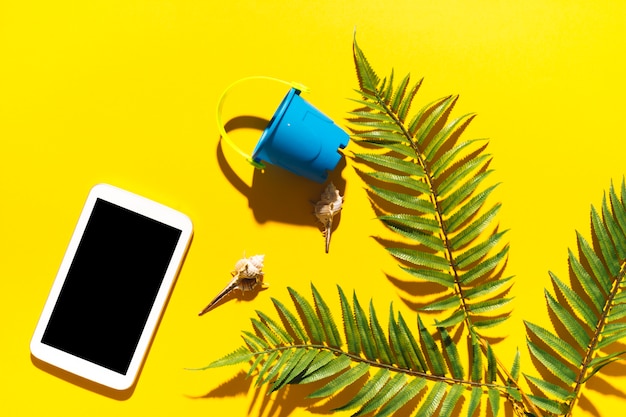 Free photo gadget bucket and palm tree leaf on bright background