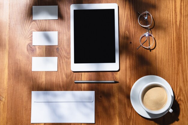 Gadgets, coffee, work tools on a wooden table indoors.